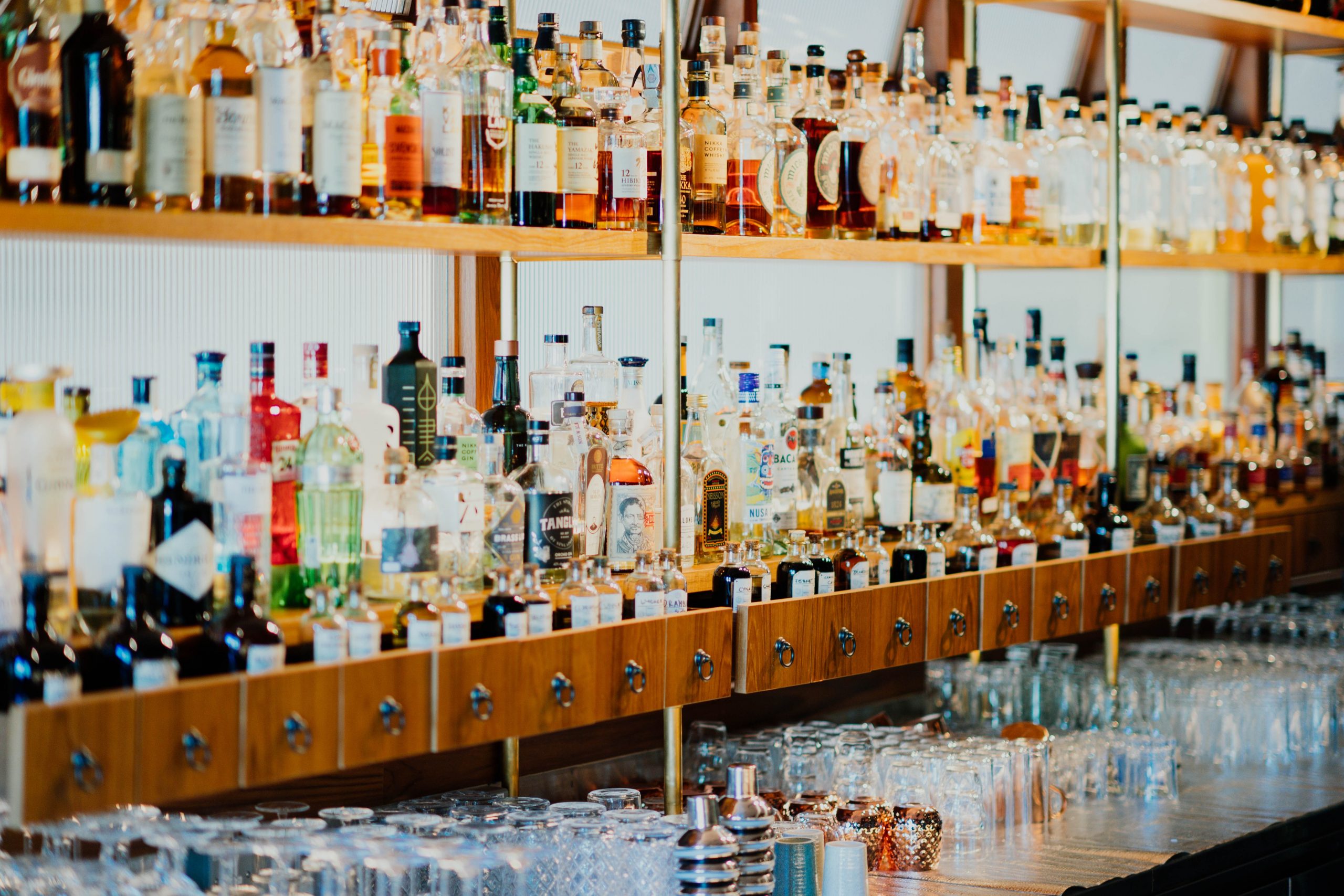 Multiple liquor bottles on a shelf in a bar