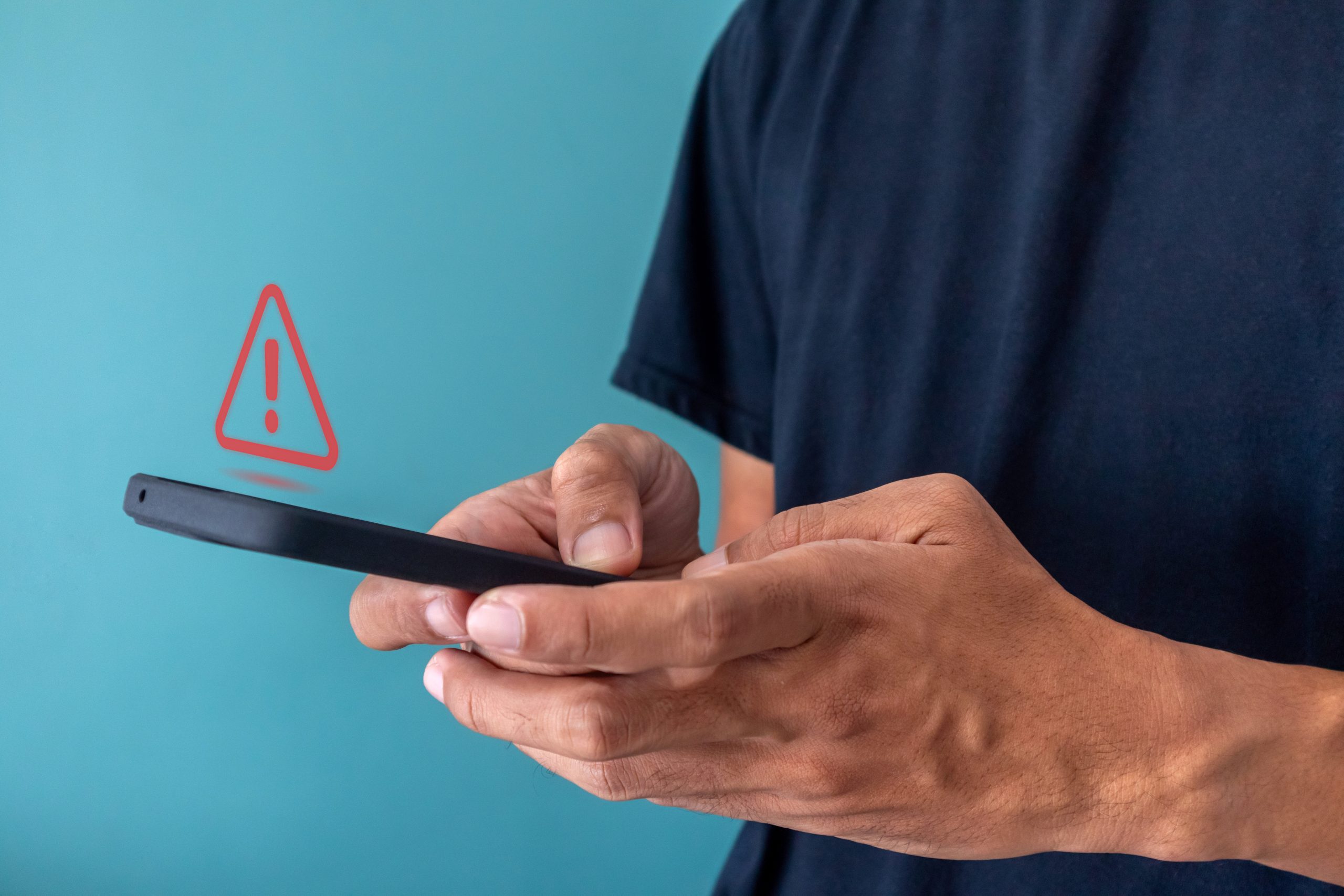 Man using a smartphone with red triangle caution warning sign fo