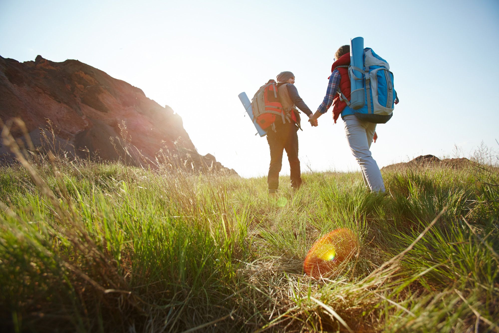 two people hiking in a field facing away from the camera